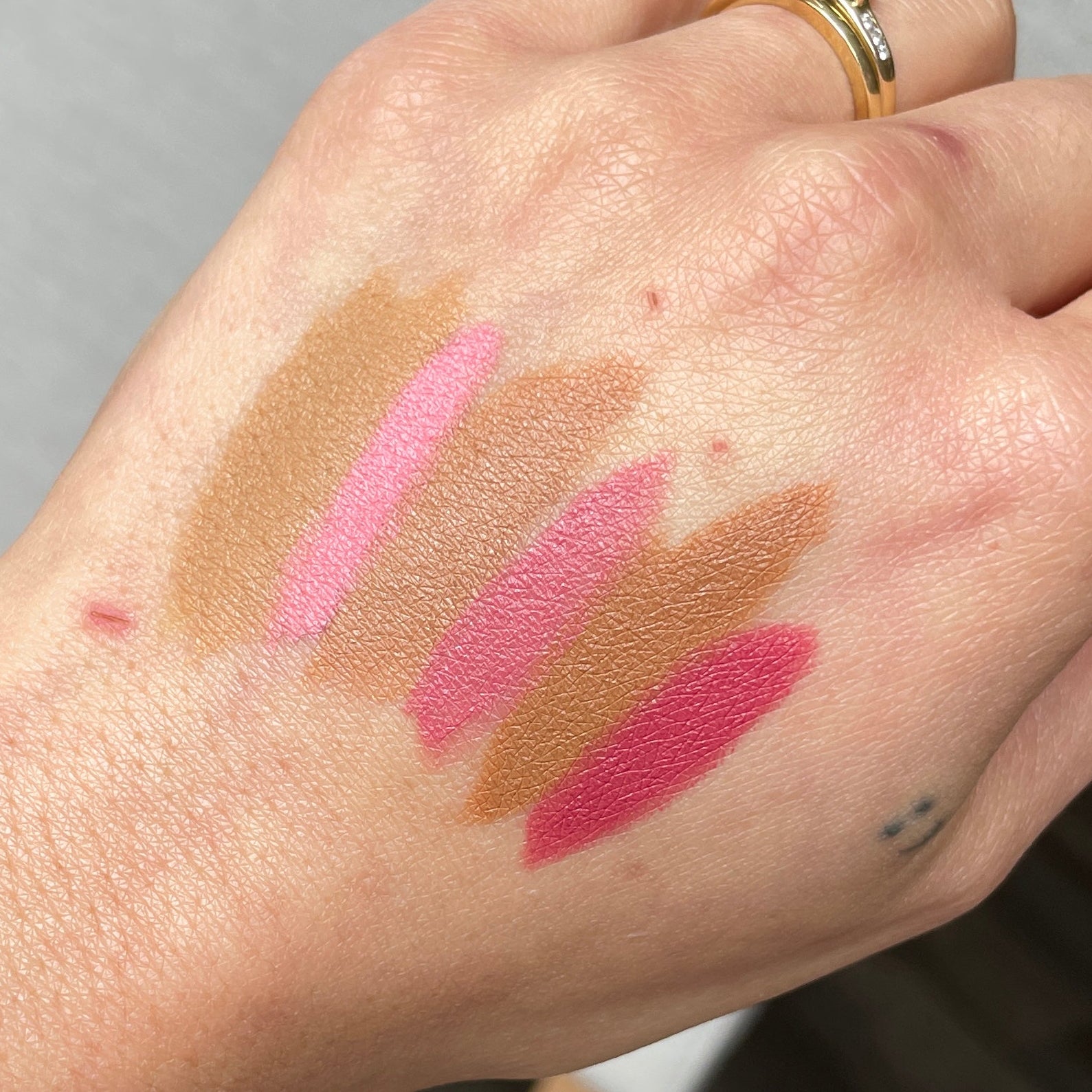 Hand with makeup swatches on a blurred indoor background